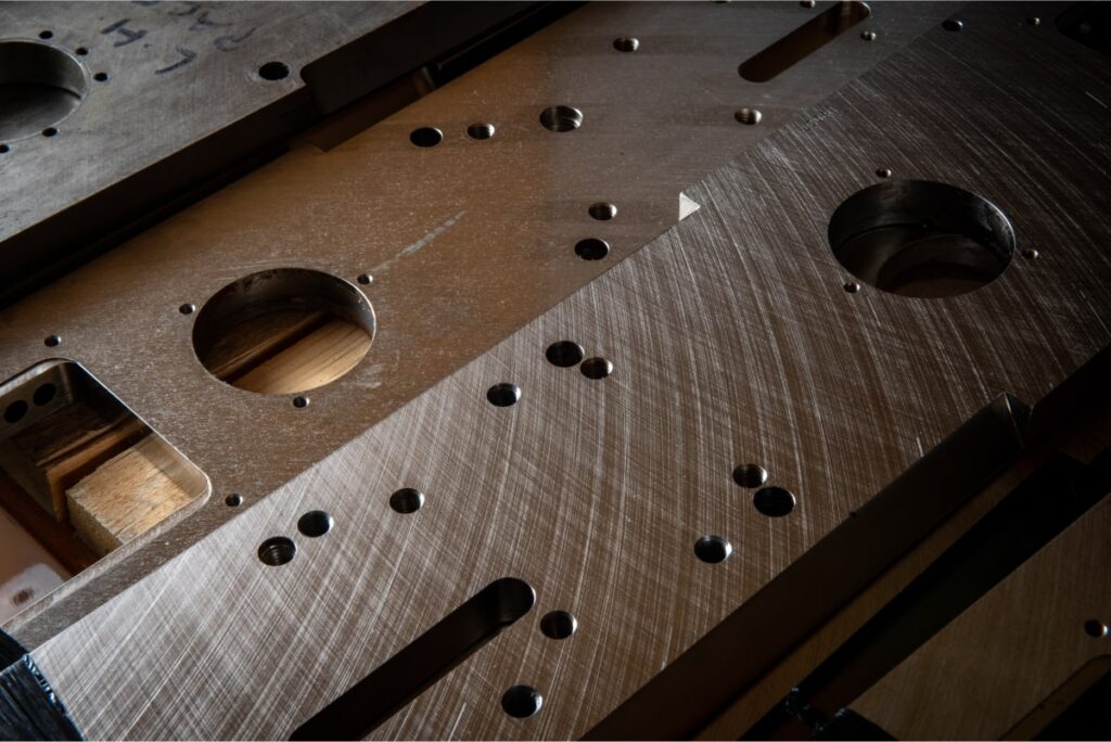 Detailed close-up of a metal plate with numerous holes, highlighting its structural features and metallic finish.